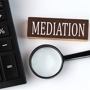 A magnifying glass, calculator, and a block of wood with MEDIATION written on it, representing divorce mediation.