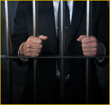 Man in suit behind prison bars: White collar crimes and fraud.