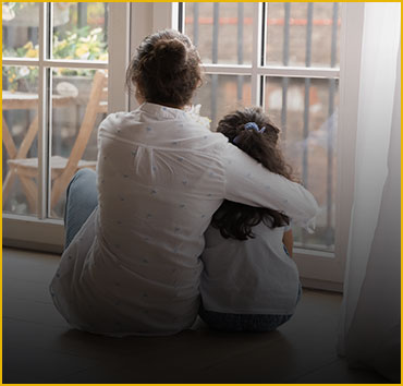 Adult hugging child, looking out window: Representing adoption.