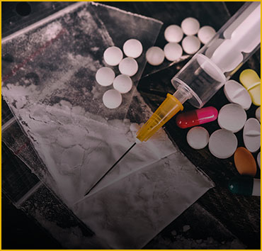 Drugs, syringe, and pills on a table, representing drug crimes.