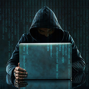 Hacker in a hoodie with a laptop, representing computer and internet crimes.