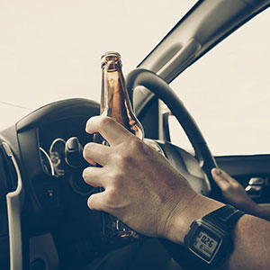 Person drinking beer while driving, representing DWI & DUI defense.
