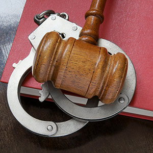 Gavel and handcuffs on a legal book, representing extradition and arrest warrants.