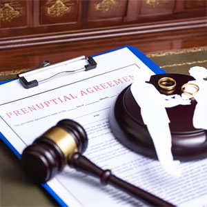 Prenuptial agreement document with a gavel and wedding rings, symbolizing legal assistance.