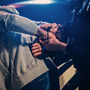 Person being handcuffed, symbolizing violent crimes and legal defense.