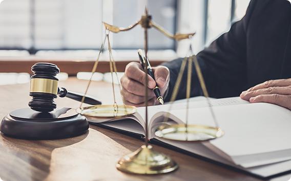 Attorney reviewing and signing legal documents at a desk with gavel and scales of justice, representing legal services and courtroom representation.